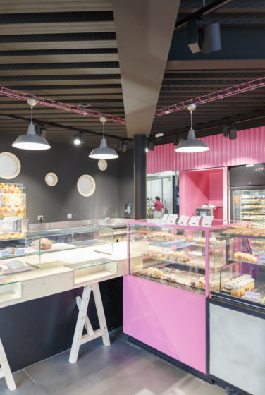 Comme à la maison BOUTIQUE à ANNECY, BOULANGERIE, vue sur l'espace boulangerie avec vitrine de présentation choux, hublot donnant sur le laboratoire, en tôle ondulé rose. Espace réalisé par le STUDIO frvr