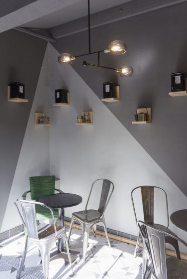épicerie sur cours à Lyon, vue intérieur de l'espace salon de thé, avec peinture géométrique gris clair et foncé, étagère bois, chaise et table acier Tolix. Conçu en collaboration, Pep's création et le studio frvr