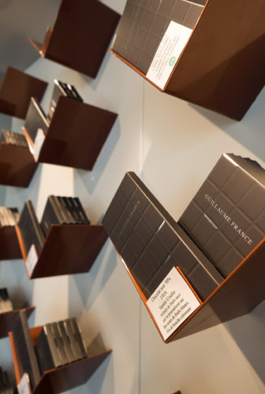 Pâtisserie Guillaume France à Lunel, vue en détail des tablettes de chocolat en libre service dans une structure en tôle acier laqué cuivre plié , boutique conçue par l'agence de design frvr.