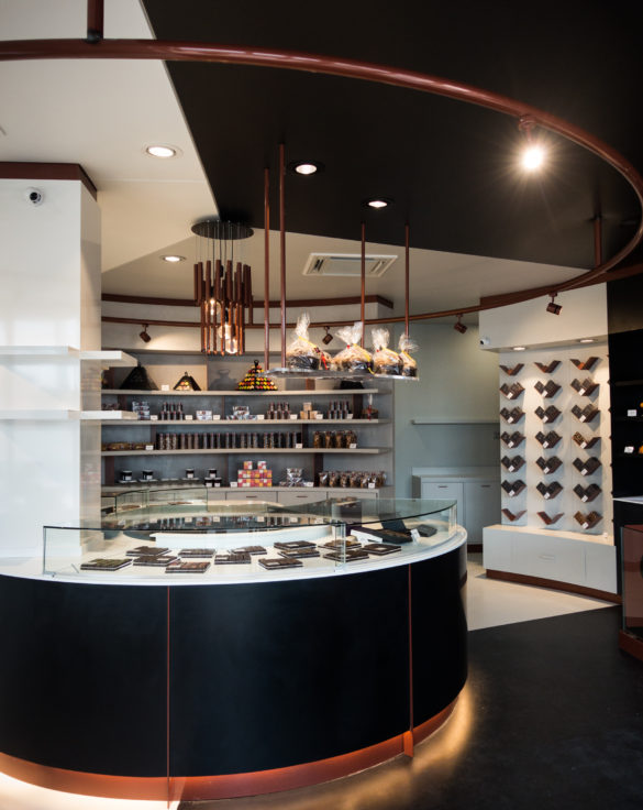 Pâtisserie Guillaume France à Lunel, vue générale avec vitrine centrale, mur à tablette chocolat, et étagère de produits sec confiture, biscuit, boutique conçue par l'agence lyonnaise de design frvr.