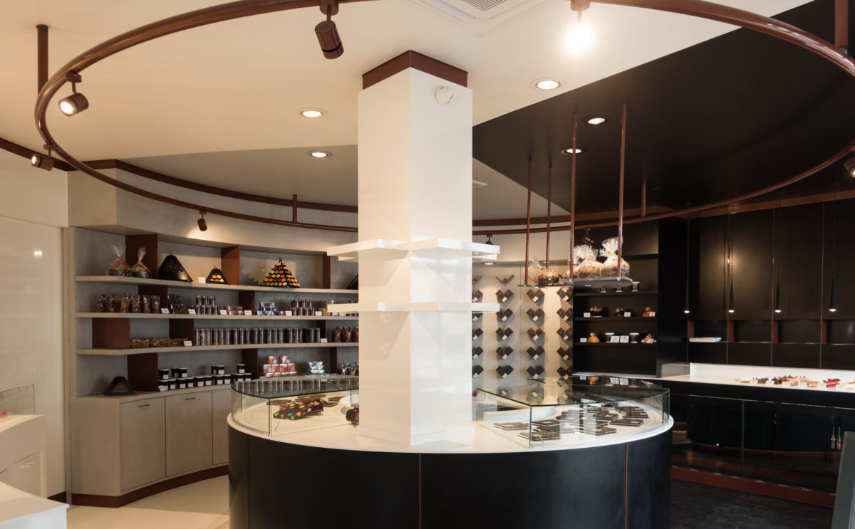 Pâtisserie Guillaume France à Lunel, vue générale avec vitrine centrale, mur à tablette chocolat, et étagère de produits secs, et vitrine pâtisserie individuelle, conçue à Lyon par l'agence de design frvrv.