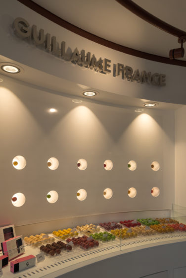 Pâtisserie Guillaume France à Lunel, vue en détail du mur macaron avec une présentation individuelle rétro éclairé, boutique conçue à Lyon par l'agence de design frvr.