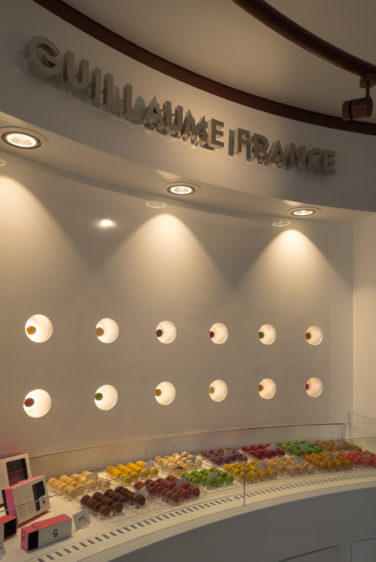 Pâtisserie Guillaume France à Lunel, vue en détail du mur macaron avec une présentation individuelle rétro éclairé, boutique conçue à Lyon par l'agence de design frvr.