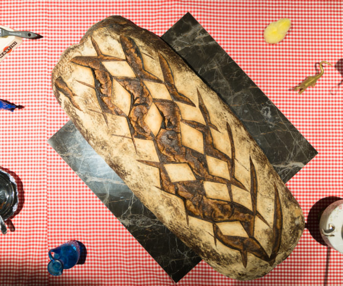 Scénographie soirée inauguration Antoinette pain et brioche détail d'un pain au levain sur marbre et nappe vichy